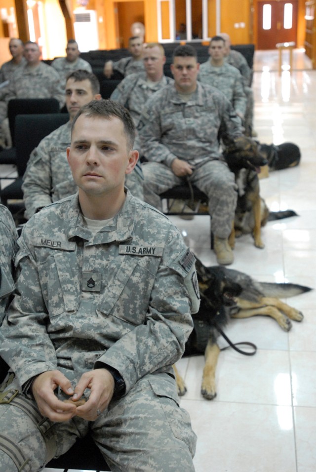 Staff Sgt. Aaron Meier, a military dog handler, sits somberly during a ceremony highlighting the life of his deceased partner, Kevin, April 13 at Camp Liberty. "Kevin was my buddy.  He was affectionate, very protective and an excellent worker," said ...