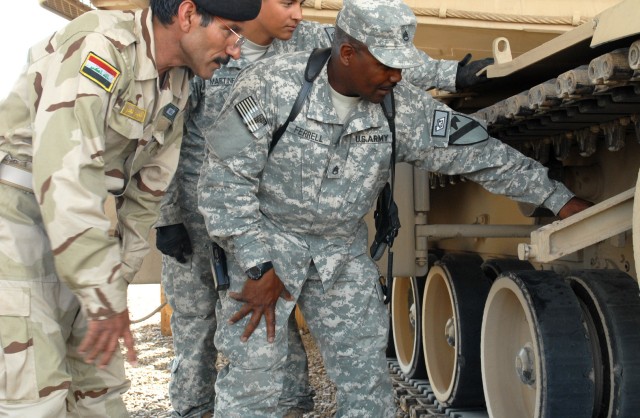 BAGHDAD - Staff Sgt. Norbert Ferrell, Company D, 2nd Battalion, 8th Cavalry Regiment, explains the finer aspects of an M1A1 Abrams tank to Iraqi Army Soldiers with the 9th IA Division at Forward Operating Base Hammer April 11. Part of the Cav....