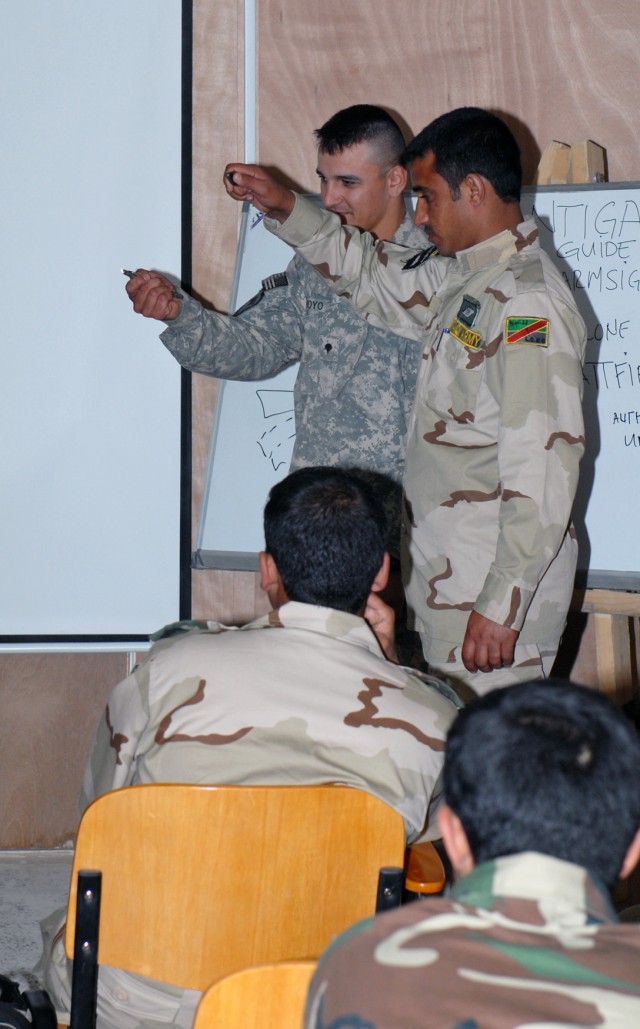 BAGHDAD – Colorado Springs, Colo. native Spc. Enrico Arroyo, Company D, 2nd Battalion, 8th Cavalry Regiment, demonstrates the use of handheld lights for nighttime hand and arm signals to Iraqi Soldiers of the 9th Iraqi Army Division April 11 at...