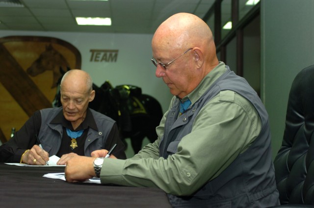 BAGHDAD - Medal of Honor recipients, retired Army Col. Robert L. Howard (left) and  retired Command Sgt. Maj. Gary L. Littrell sign autographs April 14 at Camp Liberty for military service members serving with Multi-National Division-Baghdad. When a ...
