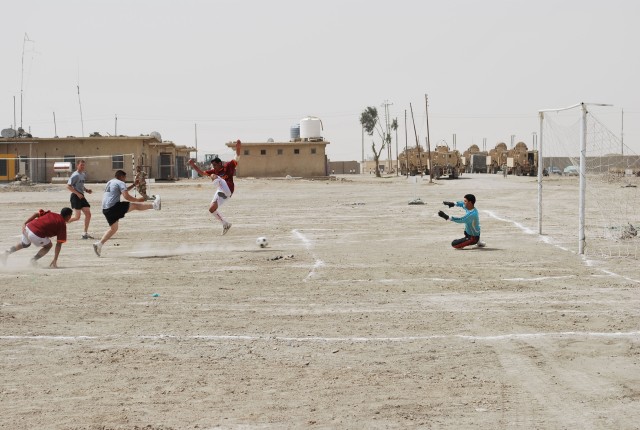 A U. S. Soldier, assigned to the 27th Brigade Support Battalion, 4th Brigade Combat Team, 1st Cavalry Division, attempts to score a goal against Soldiers from the Iraqi Army's 10th Motorized Transport Regiment during a soccer match on Camp White...