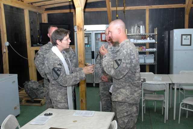 BAGHDAD - Sgt. Hugh Phillips of the 1st Battalion, 82nd Field Artillery Regiment, 1st Brigade, 1st Cavalry Division receives communion from Chaplain (Lt. Col.) Barbara Sherer, Multi-National Division-Baghdad chaplain, after the Easter service...