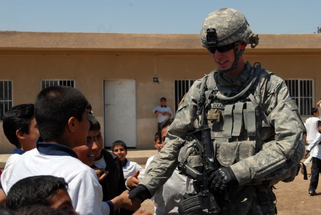 BAGHDAD - Combat medic, Spc. Caleb Eckart, from Morgantown, Ind., assigned to 1st Squadron, 7th Cavalry Regiment, shakes hands with students from the Abu Alkaseb Elementary School here, April 13. "The teachers come to class and feel safe and...