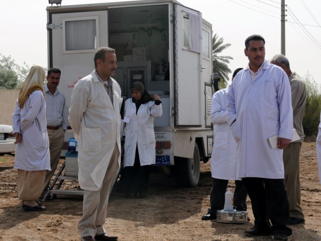 BAGHDAD - Staff from the Lutifiyah Public Health Center stand in front of their mobile medical clinic vehicle at Kinana School, April 8. The vehicle contains medical equipment and supplies to treat the patients from the local community who were...
