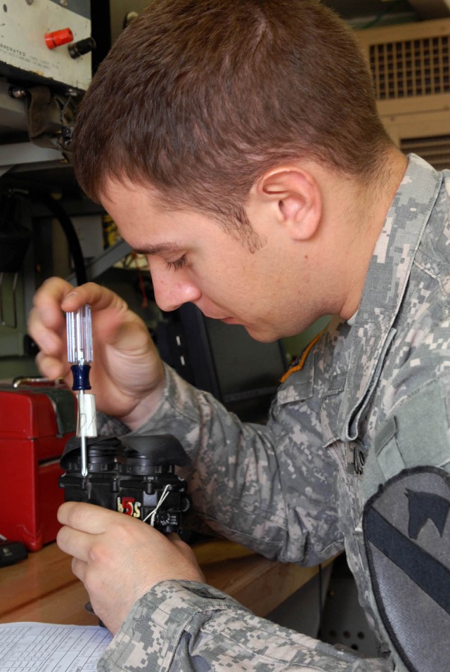 Camp Taji, Iraq- Lanark, Ill. native, Spc. Kyle Martz, special electronic device repairer for Company B, 115th "Muleskinners" Brigade Support Battalion, 1st Brigade Combat Team, 1st Cavalry Division puts a pair of AN/PVS-7B night vision goggles...