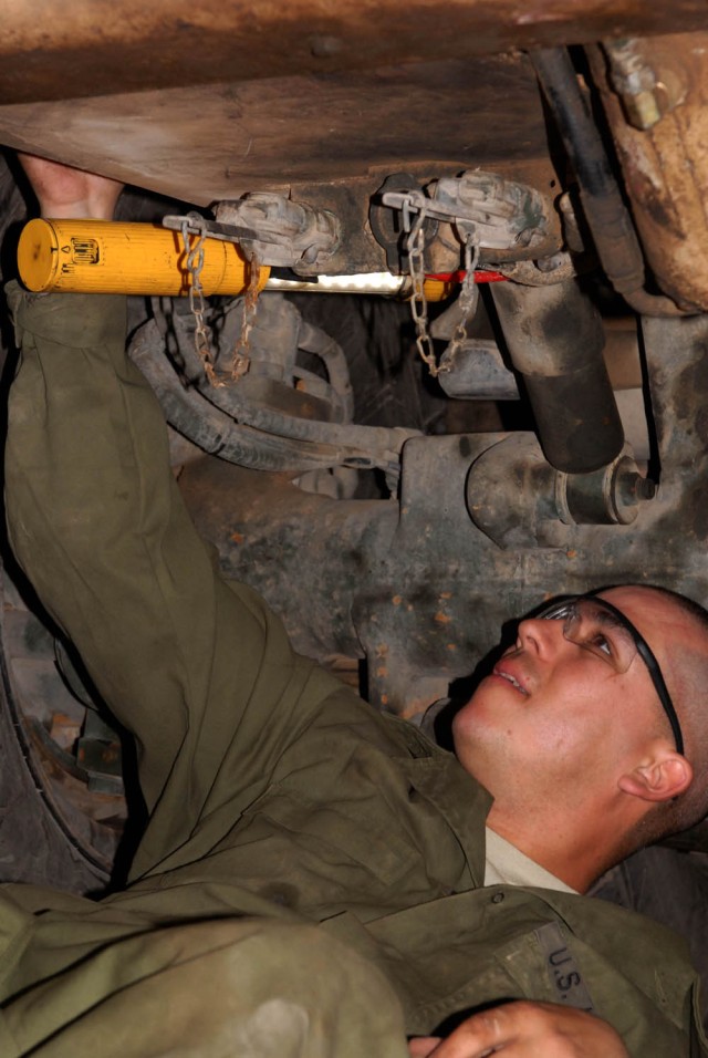 Camp Taji, Iraq - Austin, Texas native, Spc. Philip Thompson, light-wheel mechanic for Company B, 115th "Muleskinners" Brigade Support Battalion, checks for leaks April 17 here on a Palletized Load System vehicle to ensure proper performance for a...