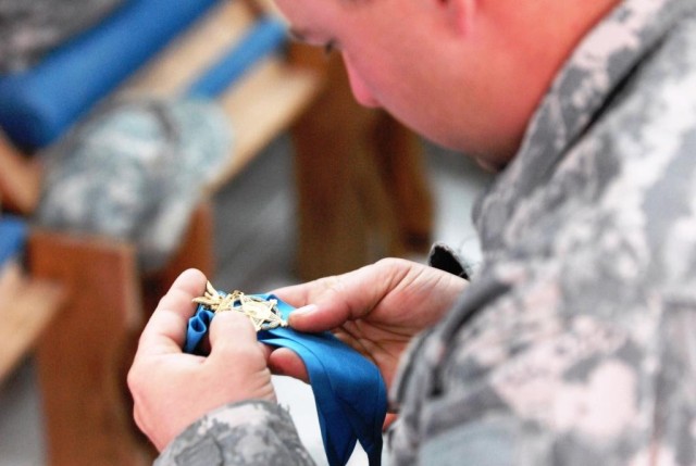 BAGHDAD - A 225th Engineer Brigade Soldier gingerly holds the nation's highest military award, the Medal of Honor. Recipients of the medal, retired Command Sgt. Maj. Gary Littrell and retired Col. Robert Howard (not pictured), made their sixth visit ...