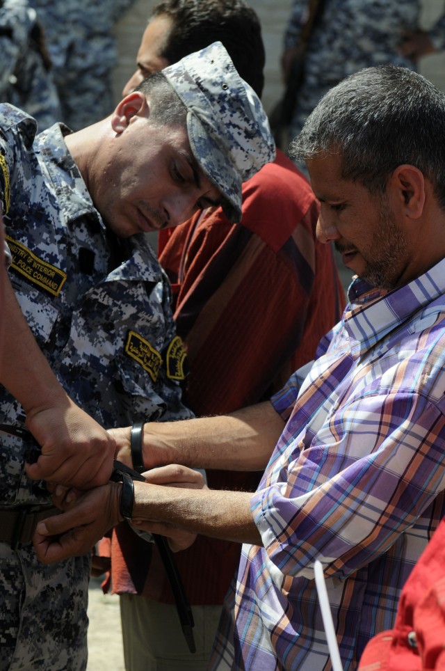 BAGHDAD-An Iraqi National Police officer from 7th Brigade, 2nd National Police Division cuts the flex cuffs off of the wrists of a former detainee during a reconciliation ceremony at Joint Security Station Dora, April 13. The former detainees were...