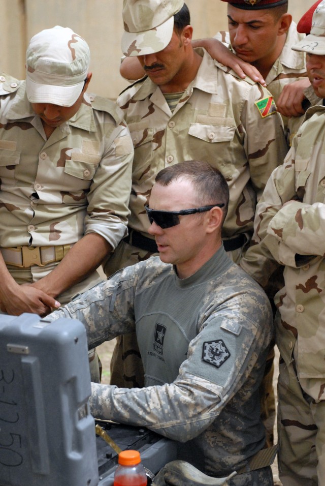 BAGHDAD - Kansas City, Mo. native, Shaun Williamson, a member of the 515th Sapper Company, 5th Engineer Battalion attached to the 225th Eng. Brigade, gives detailed instructions on how to maneuver the Talon robot via the controller box to Iraqi...