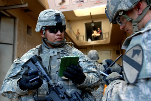 BAGHDAD - Spc. Justin Dayzie (left), a civil affairs specialist from Kaibeto, Ariz., assigned to the 450th Civil Affairs Battalion takes notes and a grid reading inside a plastics factory in Boob al-Sham here, April 14. Spc. James Powell, a cavalry s...