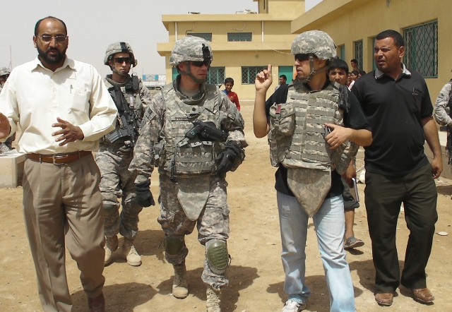 AL-MADAIN, Iraq - Sa'ad Salmin (left), the Al-Madain community sports chairman, walks with Lt. Col. Michael Shinners (center), of Alexandria, Va., during a site assessment mission April 18 in the Al-Madain area of eastern Baghdad. Shinners, who...