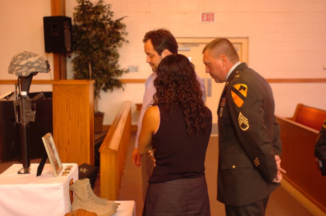 Xiomara and Antonio Mansilla, Spc. Jessica Sarandrea's mother and stepfather, and Staff Sgt. Donald Carlisle, her former supervisor, spend a moment in front of the memorial display during her memorial service April 16, at the Ironhorse Chapel on...