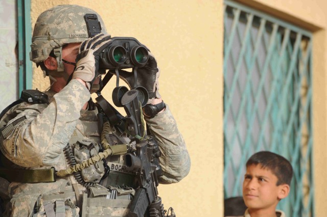 BAGHDAD - Sgt. Matt Bochiardy, of New Smyrna Beach, Fla., uses binoculars to scan the area for threats while providing security during a visit to a soccer field during a site assessment mission April 18 in the al-Madain area of eastern Baghdad. Bochi...