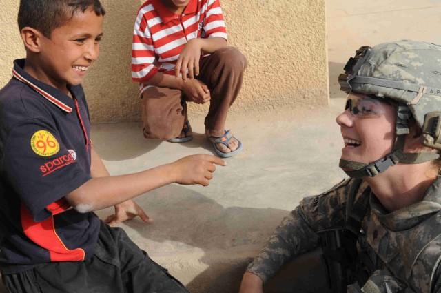 BAGHDAD - A local Iraqi boy shares a laugh with Spc. Nicole Willson, of Hillsdale, Mich., during a site assessment mission April 18 in the al-Madain area of eastern Baghdad. Willson, a combat medic assigned to the Brigade Special Troops Battalion, 3r...