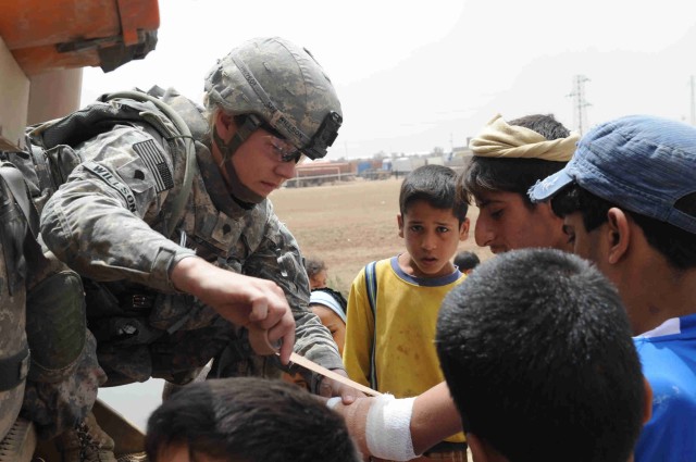 BAGHDAD - Spc. Nicole Willson, of Hillsdale, Mich., bandages the arm of local Iraqi during a site assessment mission April 18 in the al-Madain area of eastern Baghdad. Willson, a combat medic assigned to the Brigade Special Troops Battalion, 3rd Brig...