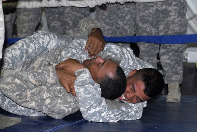 Spc. Gary Bush, a Soldier assigned to the 27th Brigade Support Battalion, 4th Brigade Combat Team, 1st Cavalry Division, holds another Soldier in a rear-naked choke during the battalion's Modern Army Combatives Tournament held in Memorial Hall on...