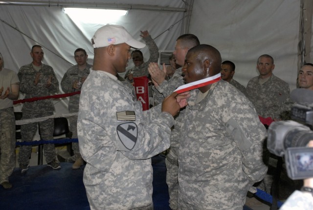 Capt. Charles Montgomery, Alpha Company commander, 27th Brigade Support Battalion, 4th Brigade Combat Team, 1st Cavalry Division, presents a medal of achievement to Pfc. Lamarcus Bailey, winner of battalion's Modern Army Combatives Tournament in...