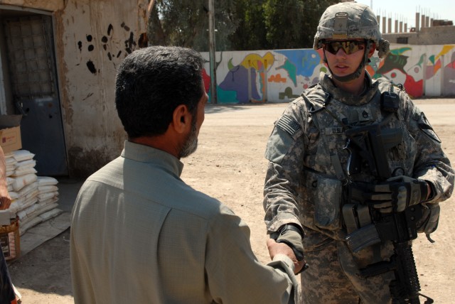 Staff Sgt. Tim Winn, a section sergeant cavalry scout from Anadarko, Okla., assigned to Apache Troop, 1st Squadron, 7th Cavalry Regiment, 1st Brigade Combat Team, 1st Cavalry Division, shakes hands with a local business owner in Thalba, April 13....