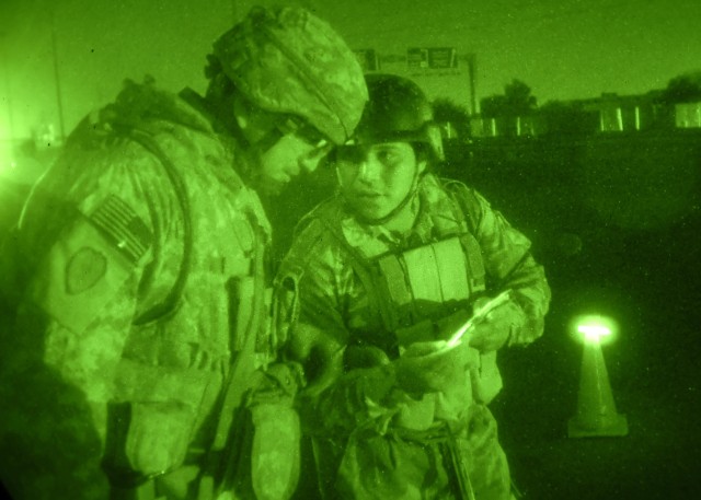 BAGHDAD - Sgt. Guadalupe Ramos (left), a native of Freer, Texas, Troop C, 5th Squadron, 4th Cavalry Regiment, 2nd Heavy Brigade Combat Team, 1st Infantry Division, looks at an Iraqi Soldier's family photos during a night mission in the Khadra neighbo...