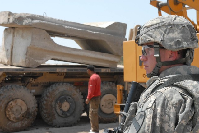 HUSSENIYAH, Iraq - Copperas Cove, Texas native, Sgt. Keith Chatelain, squad leader for Company A, 115th Brigade Support Battalion, 1st Brigade Combat Team, 1st Cavalry Division watches to ensure proper placement of barriers in order to reinforce a...