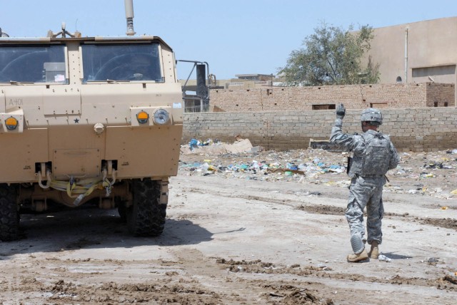 HUSSENIYAH, Iraq - Copperas Cove, Texas native Sgt. Keith Chatelain, squad leader from Company A, 115th Brigade Support Battalion ground guides a palletized load system vehicle to the other side of the National Police station to ensure proper...