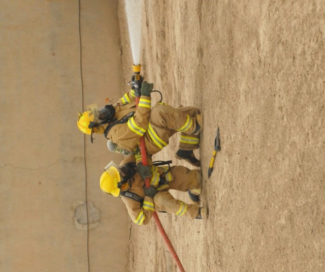 BAGHDAD - Two firefighters from the Camp Victory Fire Department extinguish a simulated fire caused by vehicle borne improvised explosive device during a mass casualty training exercise held on Victory Base Complex on Apr. 24. The training exercise s...