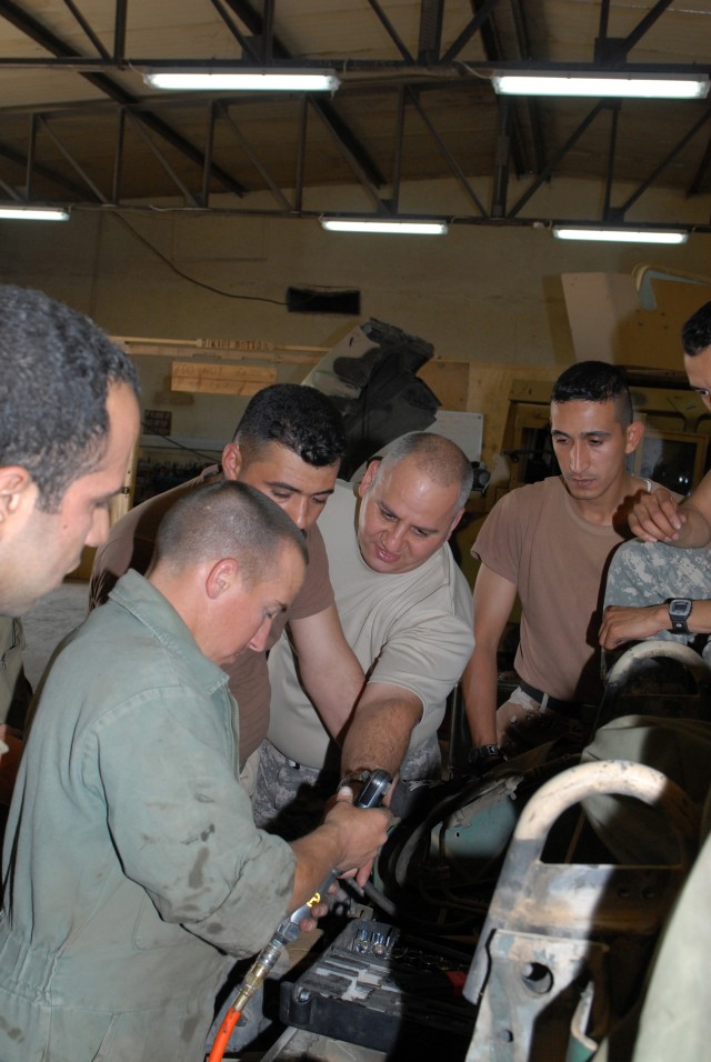 CAMP LIBERTY, Iraq - Spc. Michael Grocke (left), a mechanic from Tampa, Fla., assigned to Headquarters Support Company, Division Special Troops Battalion, 1st Cavalry Division, teaches Pvt. Hahmoud al-Saade, an Iraqi Army driver, how to use an air gu...