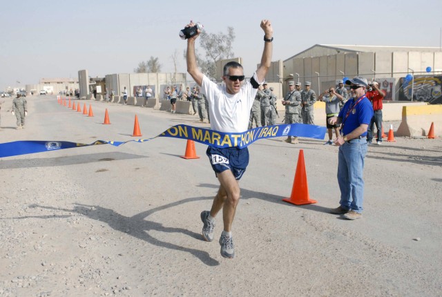 Maj. Harland Peelle, an Air Force participant stationed at Forward Operating Base Delta, raises his arms in victory as he crosses the finish line.  Peelle was the first runner to cross the finish line during the 5th Annual Boston Marathon held in COB...
