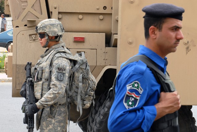 BAGHDAD - Spc. Jaclyn Guzman (left), a military policeman from Stockton, Calif., 463rd MP Company, 93rd MP Battalion, 8th MP Brigade, pulls security as her Iraqi counterpart does the same. The 463rd MPs conducted a joint patrol with local Iraqi...
