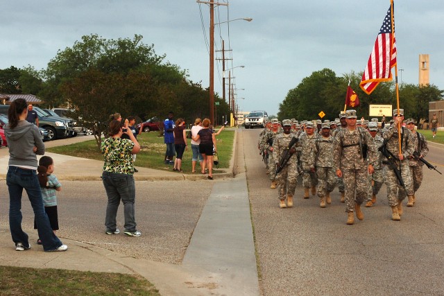 Family members watch as Lt. Col. Peter Haas, the commander of the 49th Transportation Battalion, marches a group of about 50 Soldiers down Support Ave. to the Kieschnick Physical Fitness Center April 25. The battalion deployed on a yearlong tour...