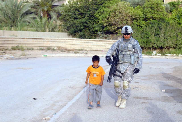 BAGHDAD - A local boy of the New Baghdad community walks to a park in his neighborhood April 30, with Sgt. Daniel Villalpando, a native of Yuma, Ariz., a military policeman assigned to Headquarters Company, Brigade Special Troops Battalion, 3rd Briga...