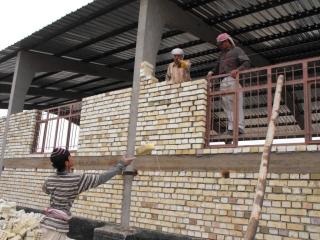 BAGHDAD - An Iraqi construction worker tosses a brick that is used to build a school supply warehouse in Abu Ghraib, May 4. The project is one of many throughout Baghdad inspected by Tioga, La., native Sgt. 1st Class Rodney Nordby, 225th Engineer...