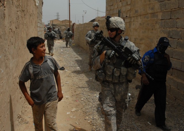 TAJI, Iraq - Spc. Adam Feldon of Allentown, Pa. (center) talks with an Iraqi boy May 4 as a patrol of Pennsylvania Army National Guard Soldiers and Iraqi Police officers moves through Taji Market, north of Baghdad. The "Keystone" Guardsmen are from C...