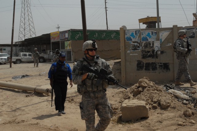 TAJI, Iraq - Spc. Adam Feldon (center) of Allentown, Pa. patrols through Taji Market, north of Baghdad, May 4 accompanied by an Iraqi Police officer and other Soldiers of Company C, 1st Battalion, 112th Infantry Regiment, 56th Stryker Brigade Combat ...