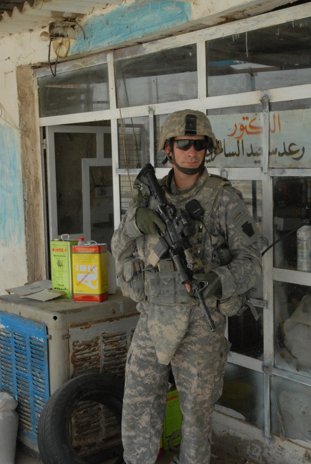 TAJI, Iraq - Staff Sgt. Corey Bukousky of Harrisburg, Pa., with Company C, 1st Battalion, 112th Infantry Regiment, 56th Stryker Brigade Combat Team pulls security in front of an Iraqi storefront May 4 during a patrol through Taji Market, north of Bag...