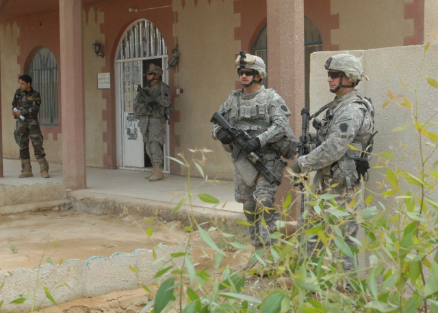 TAJI, Iraq - Staff Sergeant Corey Bukousky (right) of Harrisburg, Pa. and Spc. John Schloder of Ridgeway, Pa. keep watch in the courtyard of the Iraqi Police station in Taji, north of Baghdad, May 4 while Spc. Mike Brien of Bradford, Pa. guards the d...