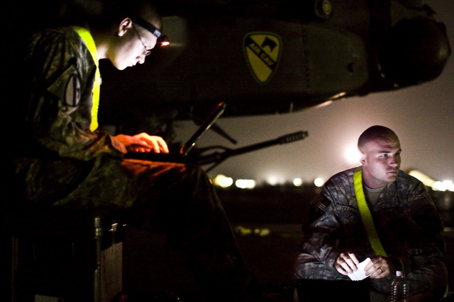 Working under the night skies, Sgt. Derrick Douglas (right) from Umatilla, Fla. and Spc. Nicholas Kirckof (left) from Roseville Minn., Both AH-64D Apache attack helicopter crew chiefs in Company B, 4th Attack Reconnaissance Battalion, 227th...
