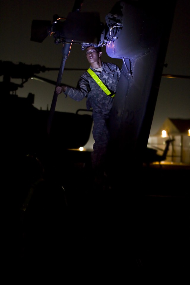 Using a head lamp as his sole source of light, Spc. Binh Miner from Dallas, an AH-64D Apache attack helicopter crew chief in Company B, 4th Attack Reconnaissance Battalion, 227th Aviation Regiment, 1st Air Cavalry Brigade, 1st Cavalry Division,...