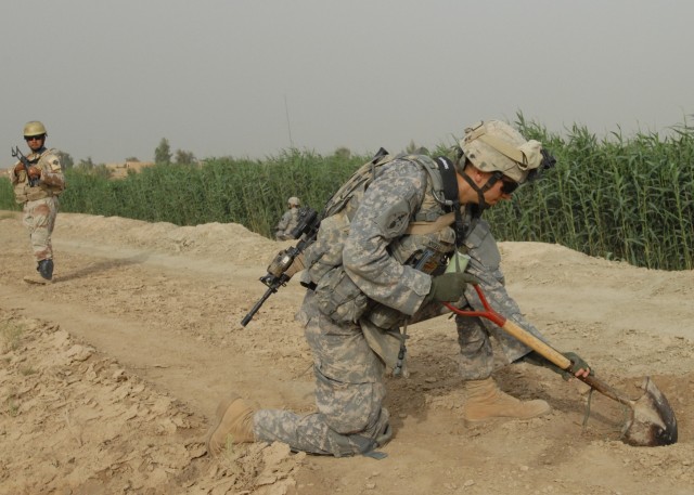 TAJI, Iraq -Sgt. Daniel Kysela (right) of Pittsburgh searches for weapons caches May 4 as an Iraqi Army Soldier and another Soldier from Company C, 1st Battalion, 112th Infantry Regiment, 56th Stryker Brigade Combat Team, pull security near Taji, nor...