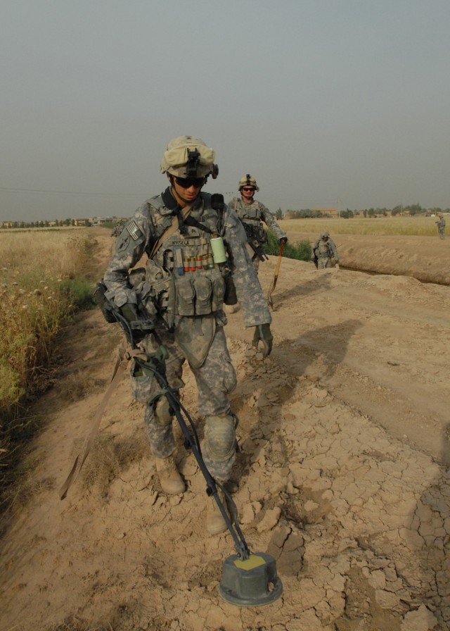 TAJI, Iraq - Pittsburgh native, Sgt. Daniel Kysela of Company C, 1st Battalion, 112th Infantry Regiment, 56th Stryker Brigade Combat Team, uses a metal detector to search for weapons caches May 4 near Taji, north of Baghdad. Kysela is followed by Spc...