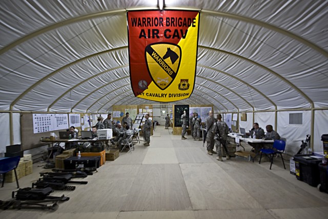 The Warriors are here! Soldiers from the 1st Air Cavalry Brigade, 1st Cavalry Division, work feverishly inside the tactical operations center at Camp Beuhring, Kuwait, May 5. The TOC is where the unit keeps track of and coordinates training among...