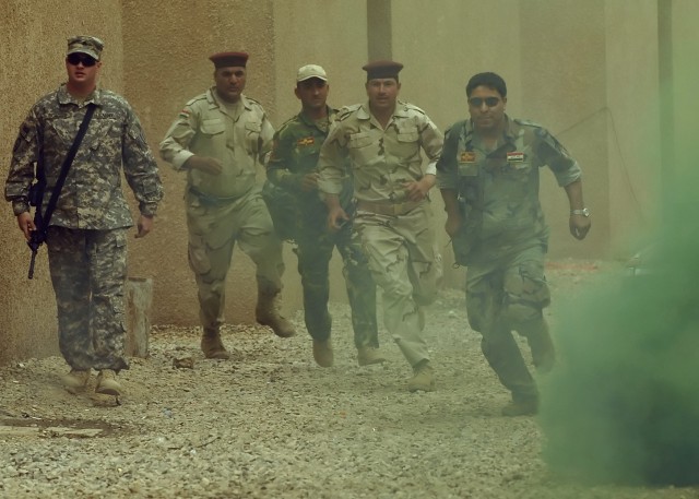 BAGHDAD - Iraqi Soldiers serving with the 6th Iraqi Army Division run to help "wounded" Iraqi Soldiers while a 5th Squadron, 4th Cavalry Regiment, 2nd Heavy Brigade Combat Team, 1st Infantry Division Soldier observes during simulated Combat Life...