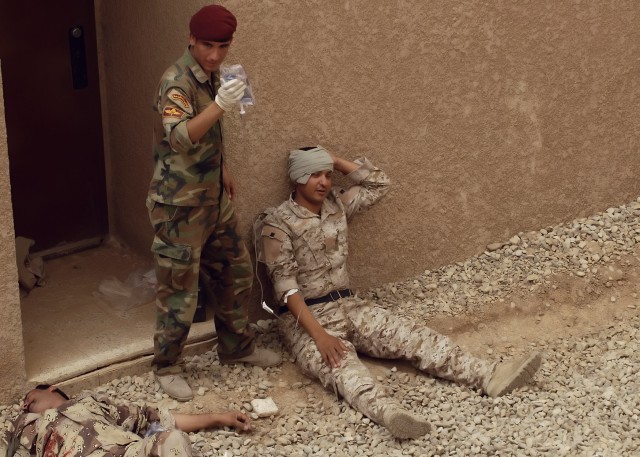 BAGHDAD - An Iraqi Soldier Serving with the 6th Iraqi Army Division holds a saline intravenous bag while "treating" the wounds of a fellow Soldier during simulated Combat Life Saver training in northwest Baghdad May 6. The Soldiers worked with...