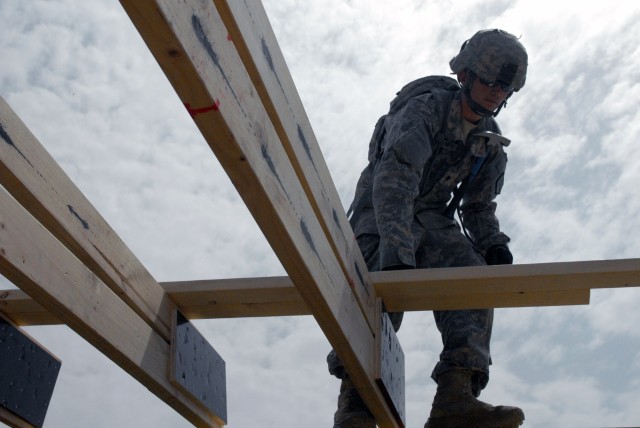 BAGHDAD - A member of the 46th Engineer Battalion, 225th Eng. Brigade, Spc. Todd Buckmeier from Wasilla, Alaska, moves purlines into place before he secures them to the B-Hut truss system May 4.  Buckmeier along with his fellow future...