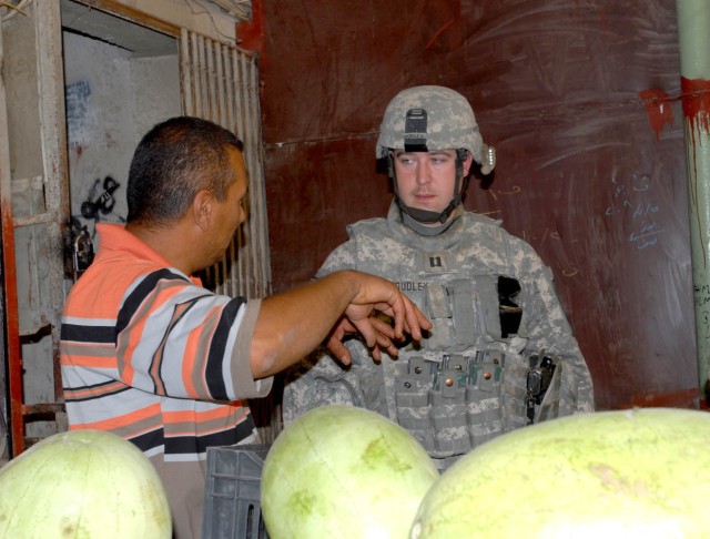 BAGHDAD - Newport News, Va. native, Capt. Jason Dudley (right), company commander for Headquarters and Headquarters Company, 1st Battalion, 5th Cavalry Regiment, attached to the 1st Brigade Combat Team, 1st Cavalry Division talks to a local shop...