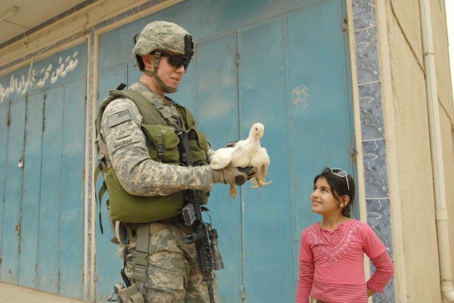 BAGHDAD - Dumont , Colo. native, Pfc. Paul Maurer (left), a driver for Headquarters and Headquarters Company, 1st Battalion, 5th Cavalry Regiment, attached to the 1st Brigade Combat Team, 1st Cavalry Division is handed a chicken during a patrol...