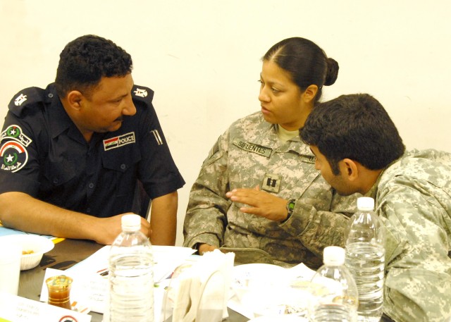 BAGHDAD - Capt. Violeta Sifuentes (center), commander, 591st Military Police Company, 93rd MP Battalion, 8th MP Brigade, Multi-National Division - Baghdad and a native of Kennisaw, Ga., discuss police security issues with Maj. Hatim (left),...