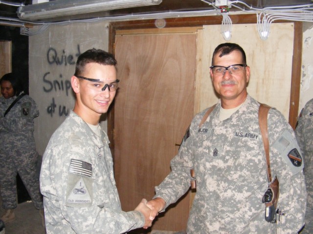 BAGHDAD - Rochester, N.Y., native, Cpl. Scott Carter, carpenter, 46th Engineer Combat Battalion (Heavy), receives a coin from Command Sgt. Maj. Joseph Major, 225th Engineer Brigade, for the work he performed while renovating the high-rise building...