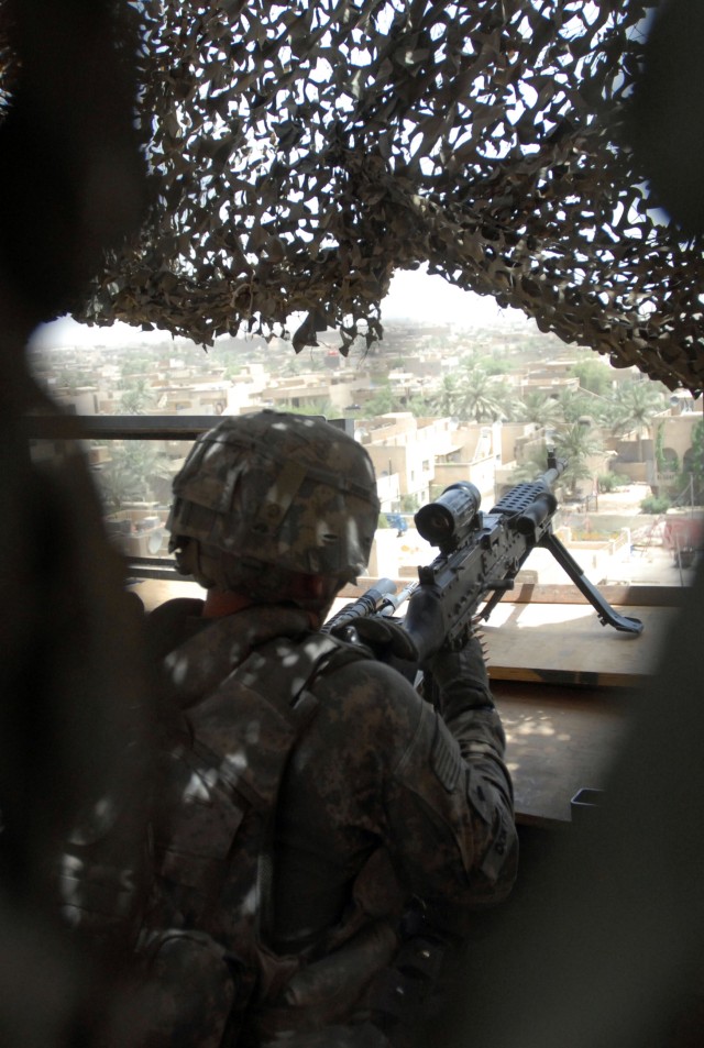BAGHDAD - Spc. Kristopher Doktor, of Peoria, Ill., a Soldier in Company A, 1st Battalion 6th Infantry Regiment, 2nd Brigade Combat Team, 1st Armored Division, Multi-National Division-Baghdad, scans his sector of fire through the sights on his M240...