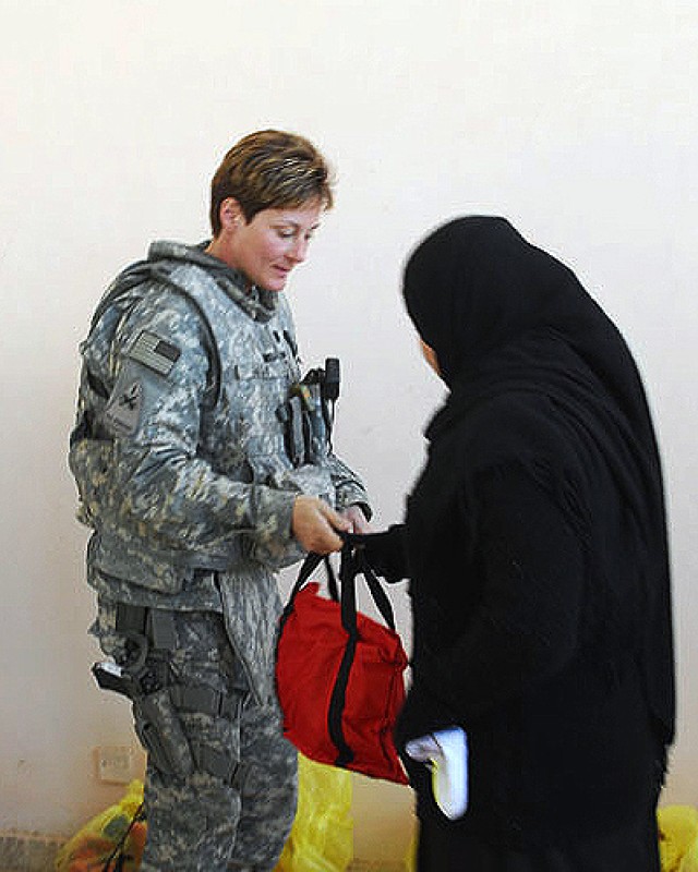 BAGHDAD - Lt. Col. Anne Resty, of Clarinda, Iowa, brigade physical therapist, and Women's Initiative Coordinator, Company C, 47th Forward Support Battalion, 2nd Brigade Combat Team, 1st Armored Division, Multi-National Division-Baghdad, hands out...